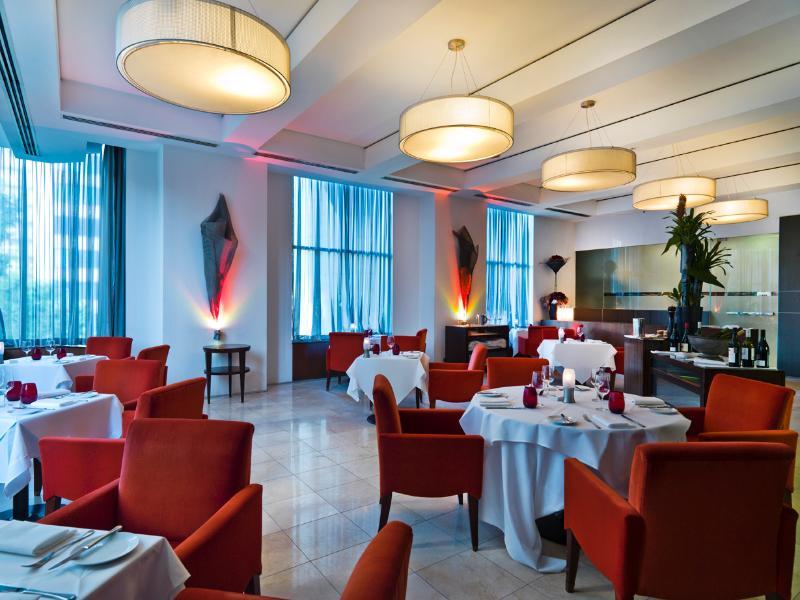 Amora Hotel Jamison Sydney Exteriér fotografie The photo shows an elegant restaurant interior. The space features stylish red chairs arranged around white tablecloth-covered tables. There are decorative elements like sculptures or artworks on the walls, and large windows covered with sheer curtai